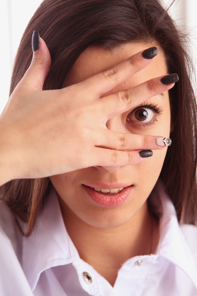Young woman peeking through fingers - Photo, Image