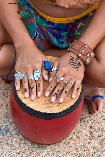 Girl's hands on bright drum, rings, mehendi, ethnic photoshooting. - Фото, изображение