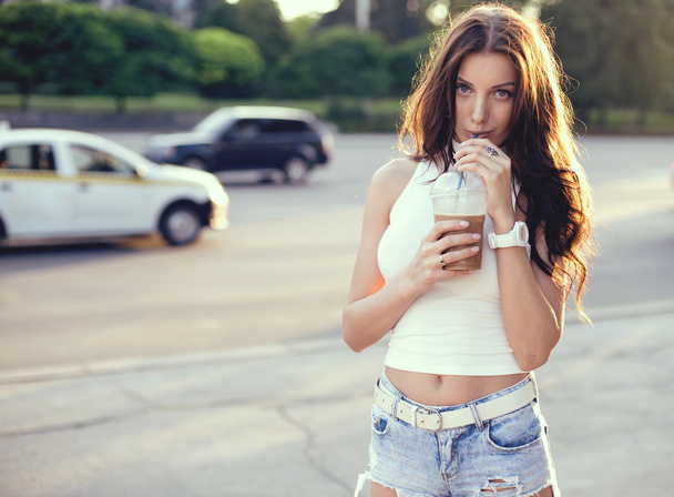 Happy beautiful girl drinking ice coffee on the sunset - Photo, Image