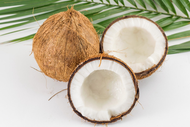 Gehalveerde en hele verse kokosnoten met bladeren - Foto, afbeelding