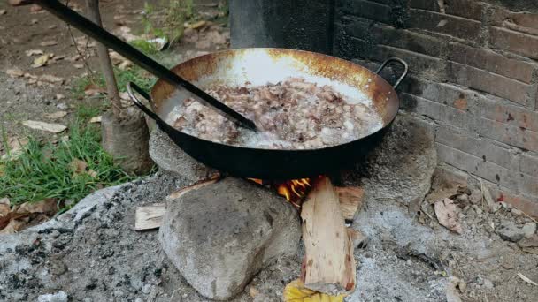 Keverés mély sütés darab sertés héja belsejében egy wok segítségével fából készült bottal nyílt tüzet  - Felvétel, videó