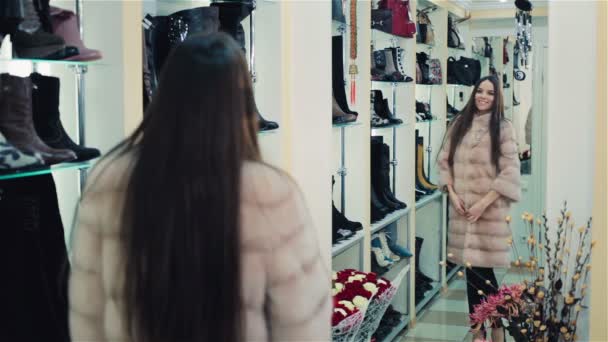 Красива дівчина з коричневим волоссям вибирає шубу в магазині. Шопінг. серії
. - Кадри, відео
