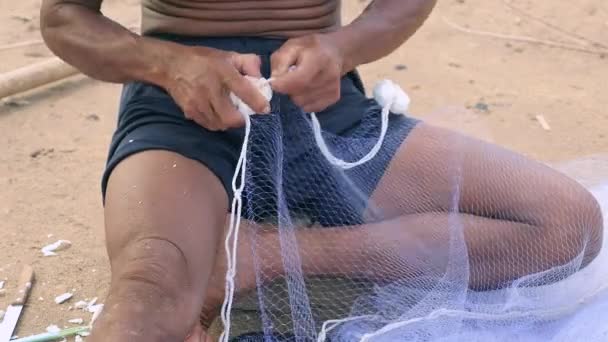 Primer plano del pescador utilizando una aguja de red de pesca para reparar una red
 - Metraje, vídeo
