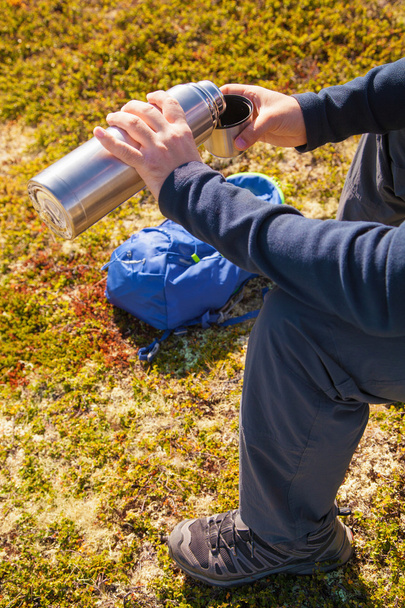 熱いお茶を魔法瓶を屋外に保持している男。ハイキングやレジャー - 写真・画像