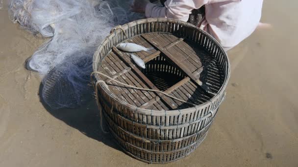 Fisher quitar la captura de pescado enredado y mantenerlo en una cesta de bambú
 - Imágenes, Vídeo