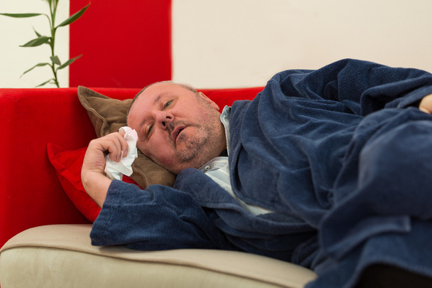 Sick man lying down on couch with high fever - Photo, Image