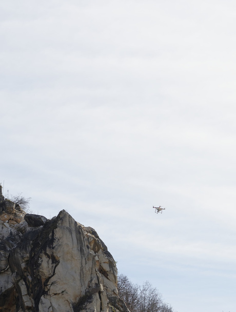 um drone voando contra um céu azul em uma pedreira de mármore
 - Foto, Imagem