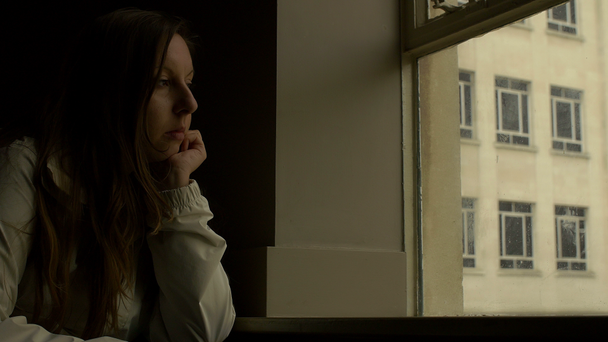 Szomorú lány közelében ablak gondolni valamit - Felvétel, videó