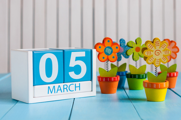 5 maart. Afbeelding van 5 maart houten kleur kalender met bloem op witte achtergrond. Eerste lente, lege ruimte voor tekst - Foto, afbeelding