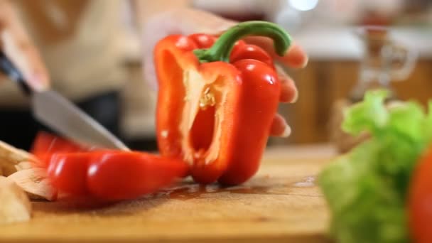 Woman hands slicing sweet Red Bell Pepper on a wooden cutting board - Imágenes, Vídeo