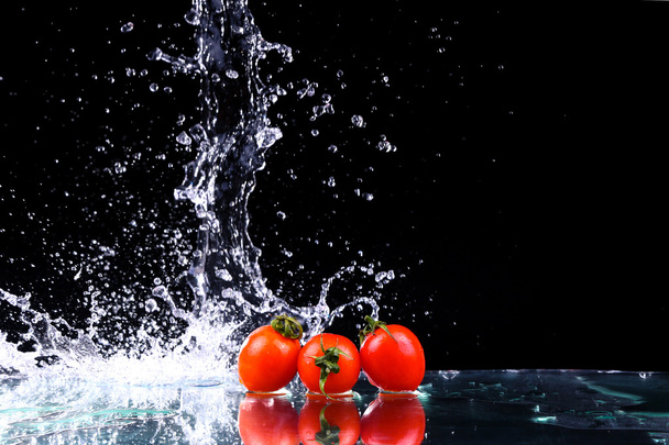 Studio s zmrazit pohyb cherry rajčat ve vodě stříkající na černém pozadí s kopií prostor - Fotografie, Obrázek