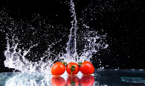 Studio shot with freeze motion of cherry tomatoes in water splash on black background with copy space - Φωτογραφία, εικόνα