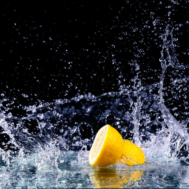 Sliced lemon in the water on black background - Foto, afbeelding