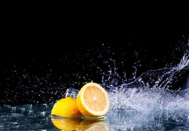 Sliced lemon in the water on black background - Photo, Image