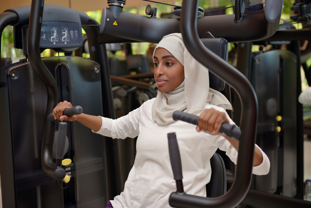 Молодая арабская мусульманка, корчащаяся в спортзале
 - Фото, изображение