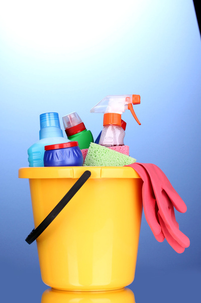 Balde com itens de limpeza em fundo azul
 - Foto, Imagem