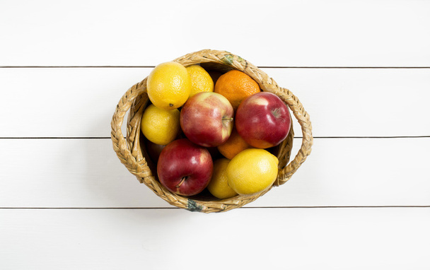 fruits in a wicker basket on the white wooden table - Photo, Image
