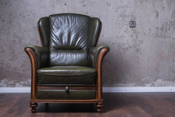 Зеленое кожаное кресло перед стеной
 - Фото, изображение