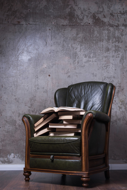 Зеленое кожаное кресло с книгами перед стеной
 - Фото, изображение