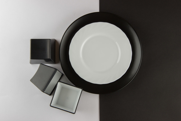 eine Reihe flacher Teller und Tassen auf schwarzem und weißem Hintergrund - Foto, Bild