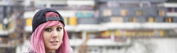 woman with piercings and pink hair at housing estate - Photo, Image