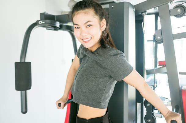 Mujer asiática haciendo ejercicio en máquina de prensa de hombro en el gimnasio
 - Foto, Imagen
