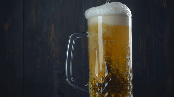 暗い背景の木の上のグラスにビールを注ぐ. - 映像、動画
