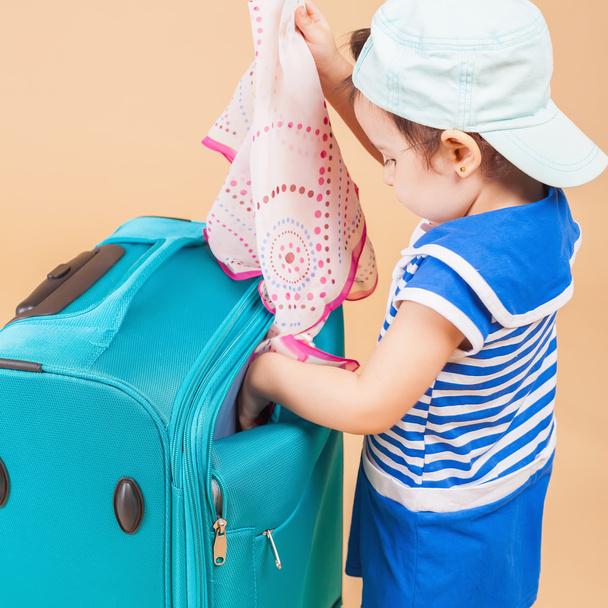 Niño empaca sus cosas, ropa en el equipaje
 - Foto, Imagen