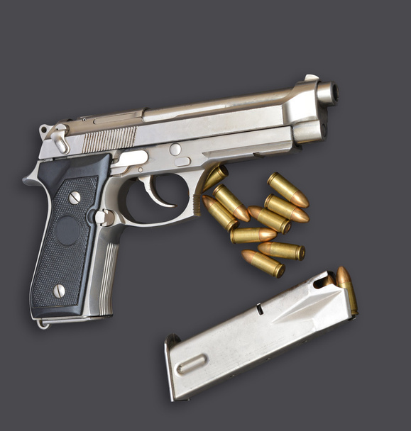 Pistolet automatique avec chargeur et balles sur fond gris
 - Photo, image