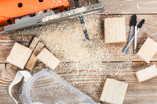 Electric jigsaw with many wooden bricks full of sawdust. - Фото, изображение