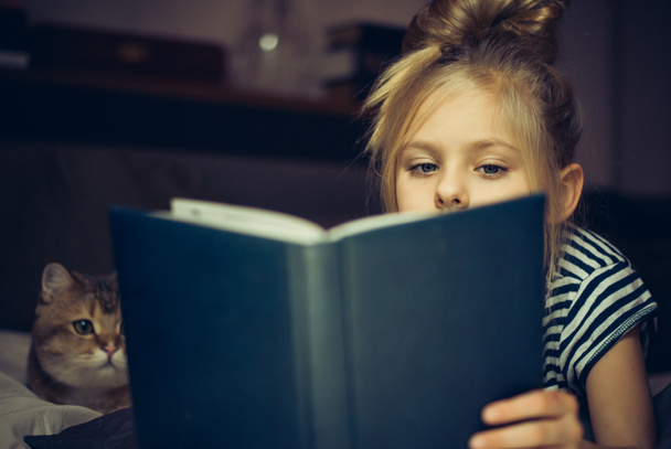 junges Mädchen liest einer Katze Buch vor - Foto, Bild