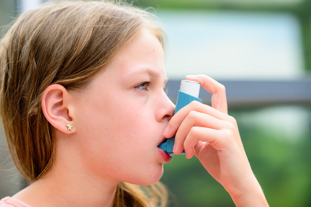Girl uses an inhaler during an asthma attack - Foto, imagen