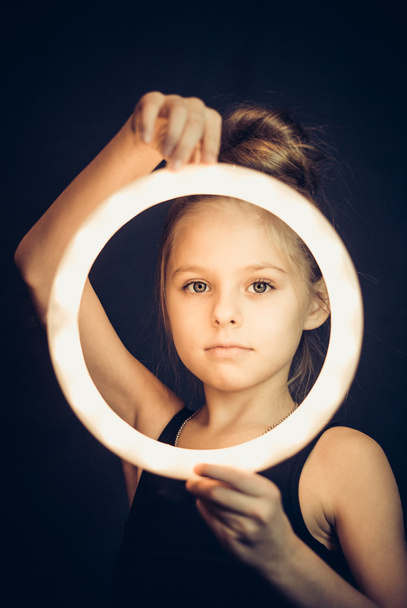 Όμορφη νεαρή κοπέλα γυμναστής κρατώντας ένα λαμπερό κύκλο - Φωτογραφία, εικόνα