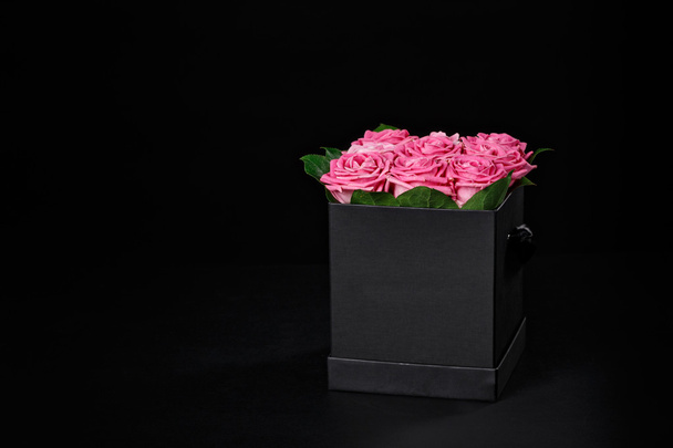 Pink roses in a small square black gift box on a black backgroun - Valokuva, kuva