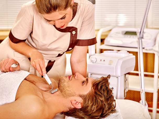 Jeune homme recevant un massage facial électrique
. - Photo, image