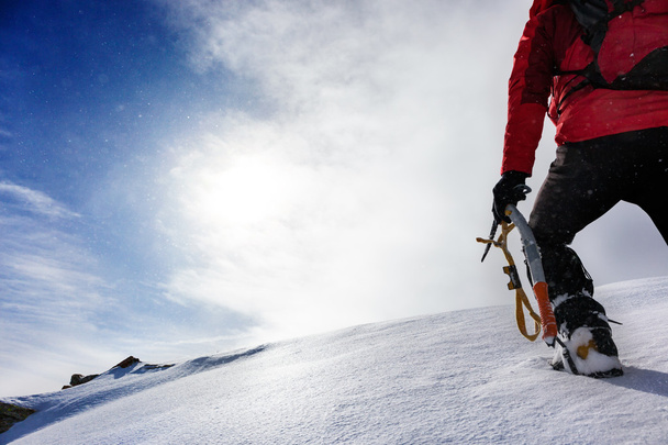 Bergsteiger erklimmt einen verschneiten Gipfel - Foto, Bild
