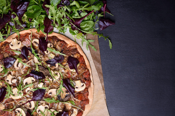 Italian Pizza and spring salad mix on dark wooden background. Overhead view, copy space. - Photo, Image