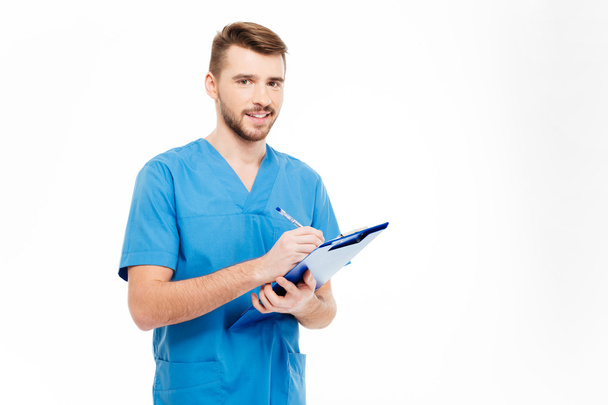 Happy male doctor standing with clipboard - Photo, image