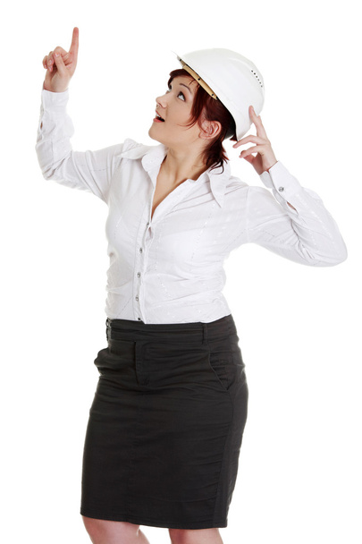 Businesswoman in white helmet pointing up. - Foto, afbeelding