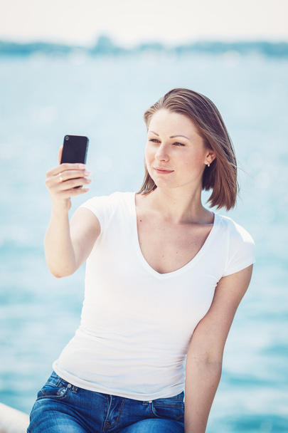 Dziewczyna kobieta patrząc na telefon komórkowy co selfie - Zdjęcie, obraz