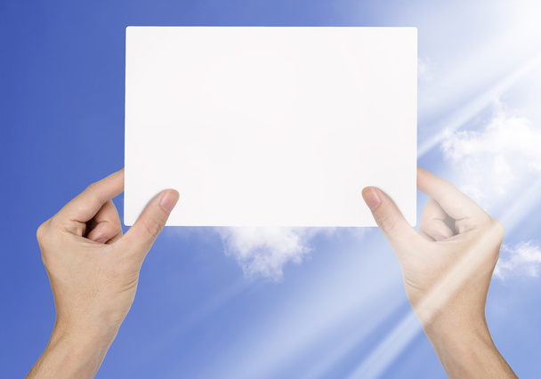 Uomo d'affari mano in possesso di carta bianca su sfondo cielo blu
 - Foto, immagini