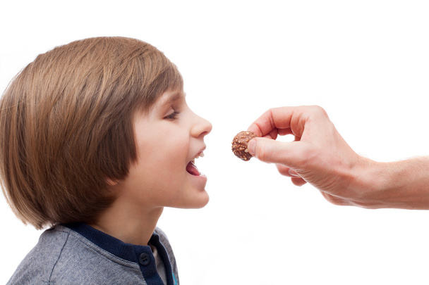boy bites chocolate ball - Fotoğraf, Görsel