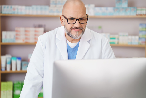 Pharmacist checking information on his computer - Фото, изображение