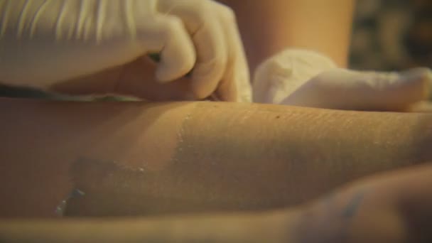 Cosmetólogo en guantes haciendo proceso de depilación en salón
 - Metraje, vídeo