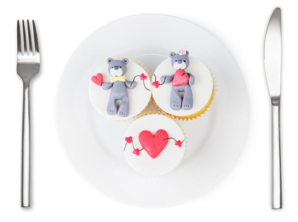 Cupcakes con oso de peluche y corazones en plato aislado
 - Foto, Imagen