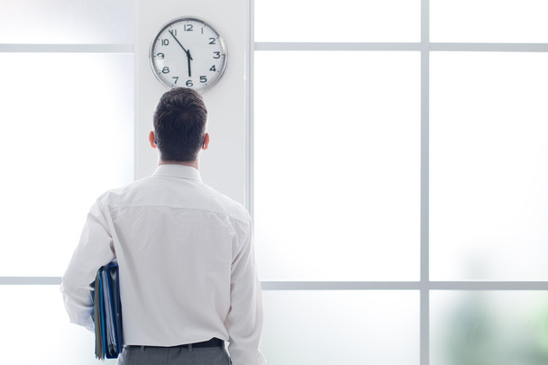 Businessman staring at the clock - Фото, изображение