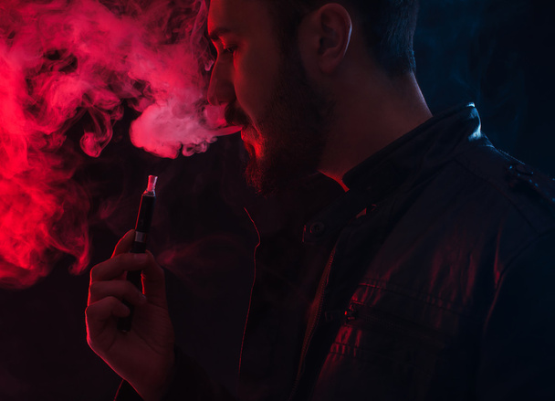 barbuto uomo elegante in possesso e fumare sigaretta elettronica
 - Foto, immagini