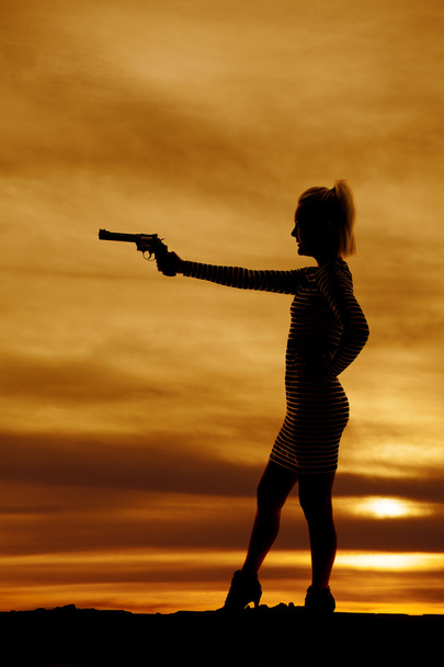 silhouette of a woman in a short dress pointing a gun - Foto, afbeelding