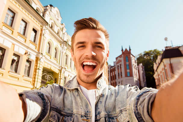 Cheerful happy man making selfie photo on the street - Fotó, kép