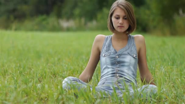 mladá žena sedící tráva - Záběry, video
